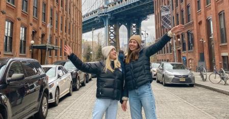 two au pairs posing with the booklyn bridge in the background