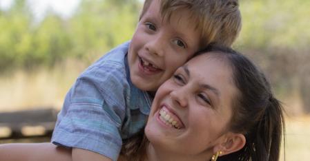 smiling au pair with host boy on her back