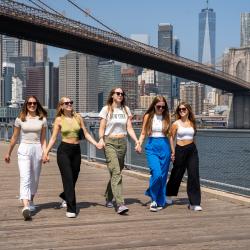group of smiling au pairs walking together by the Brooklyn Bridge.