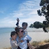 woman on the beach carrying two kids