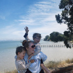 woman on the beach carrying two kids